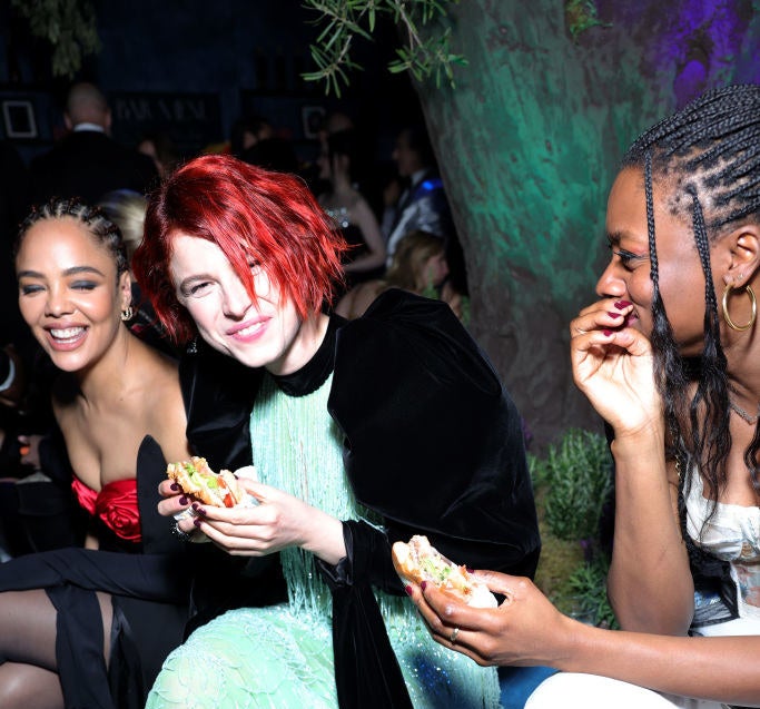 Tessa sitting next to two people who are happily munching on their burgers while she smiles