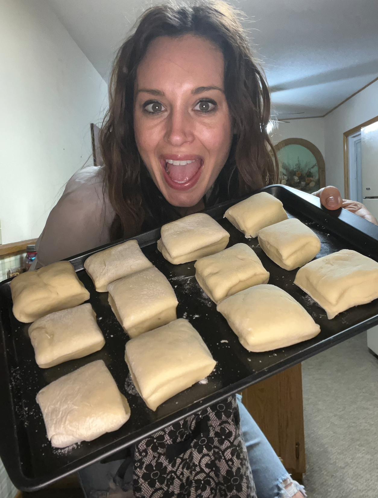 Krista happily holding a tray of 12 risen rolls