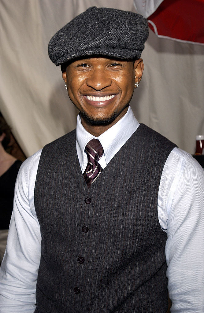 closeup of Usher smiling wearing a newsboy cap