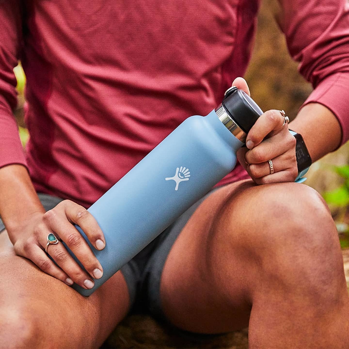 a person holding their water bottle on a hike