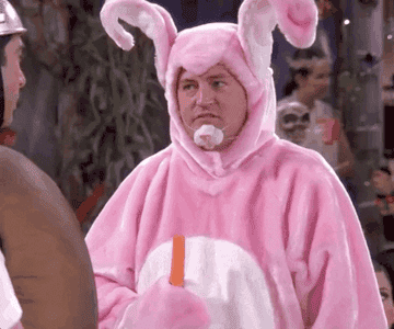 Chandler from friends chewing a carrot while dressed as easter bunny