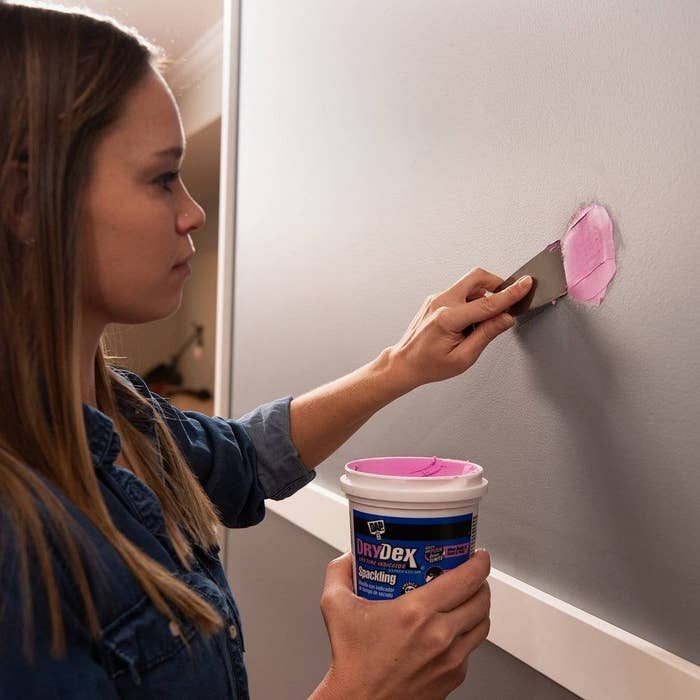 someone applying the spackle onto the wall