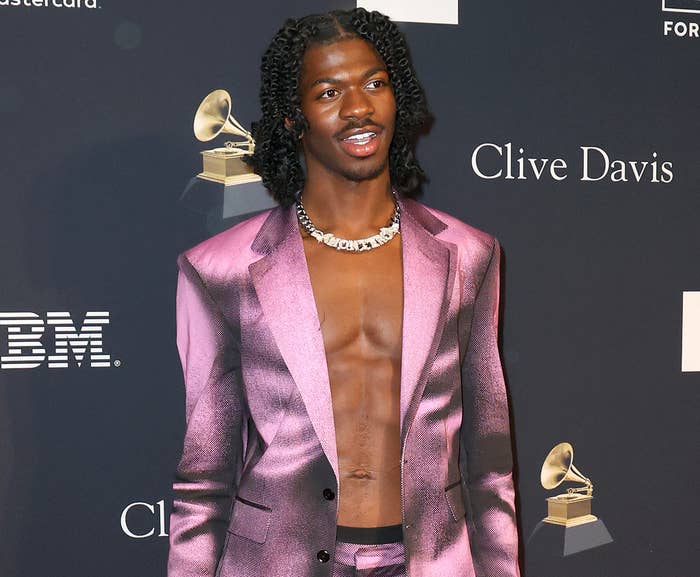 A close-up of Lil Nas at the Grammys, in a shiny suit jacket and no shirt