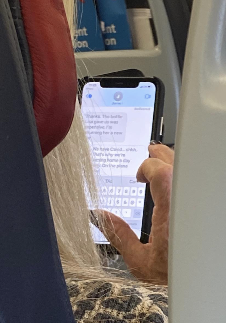 A woman on a plane texting someone that she has COVID