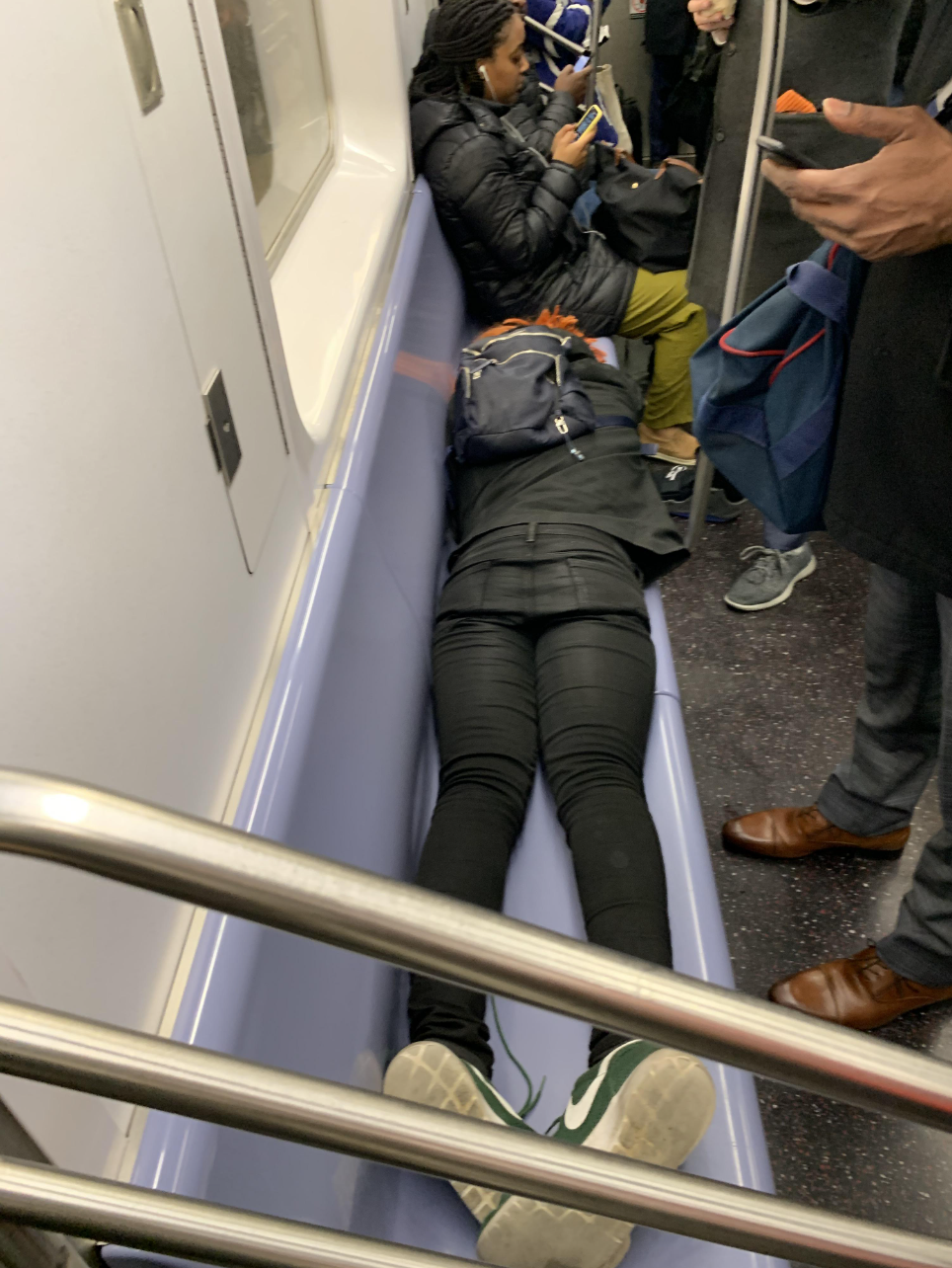 A woman laying down on the subway seat