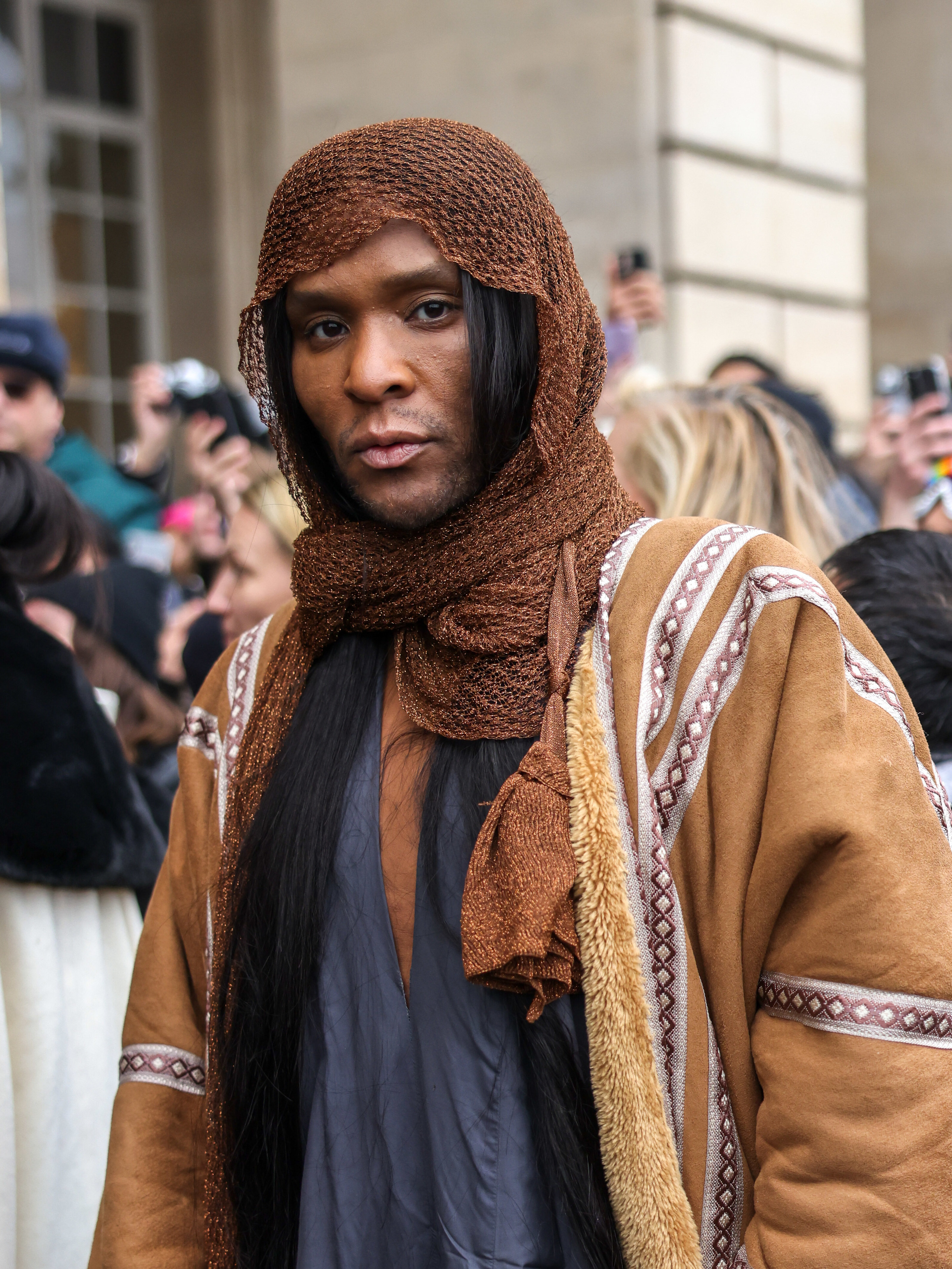 Law Roach looks into the camera, wearing a brown headscarf and full high-fashion outfit outside at an event