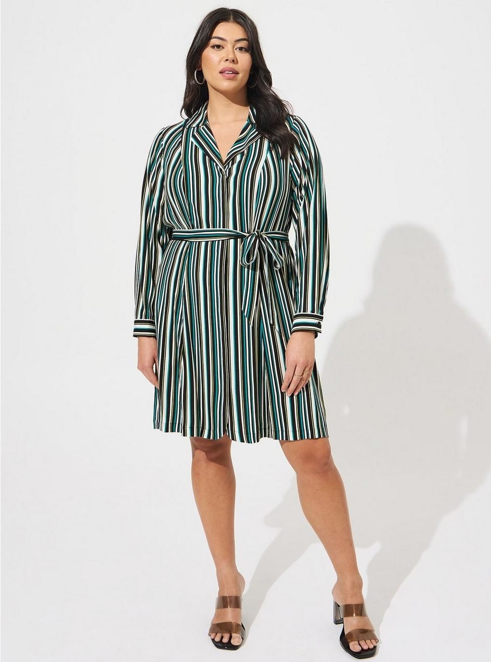 Model wearing blue, brown, and black striped wrap dress with brown sandals