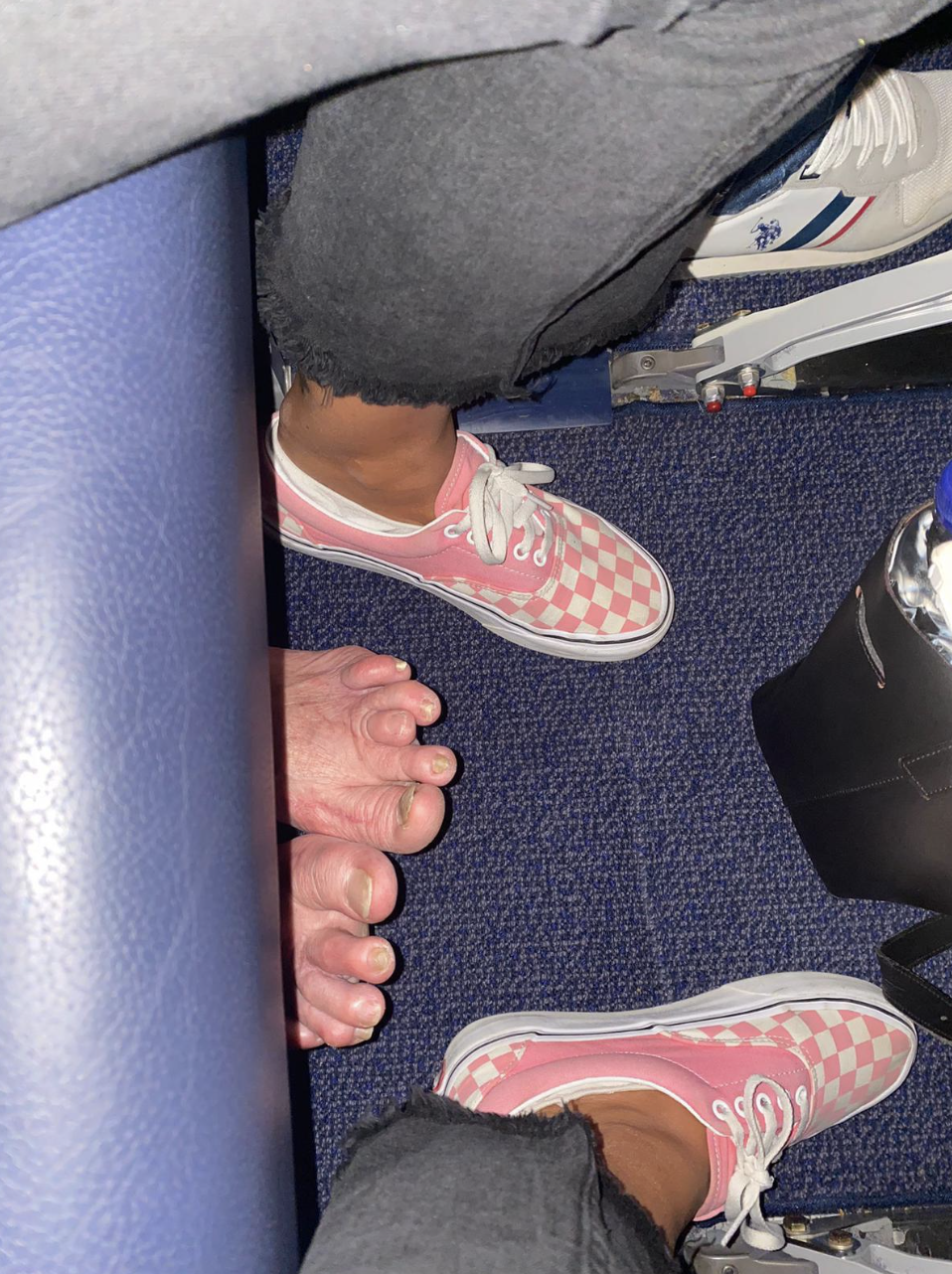 Someone&#x27;s feet peeking out under an airplane seat