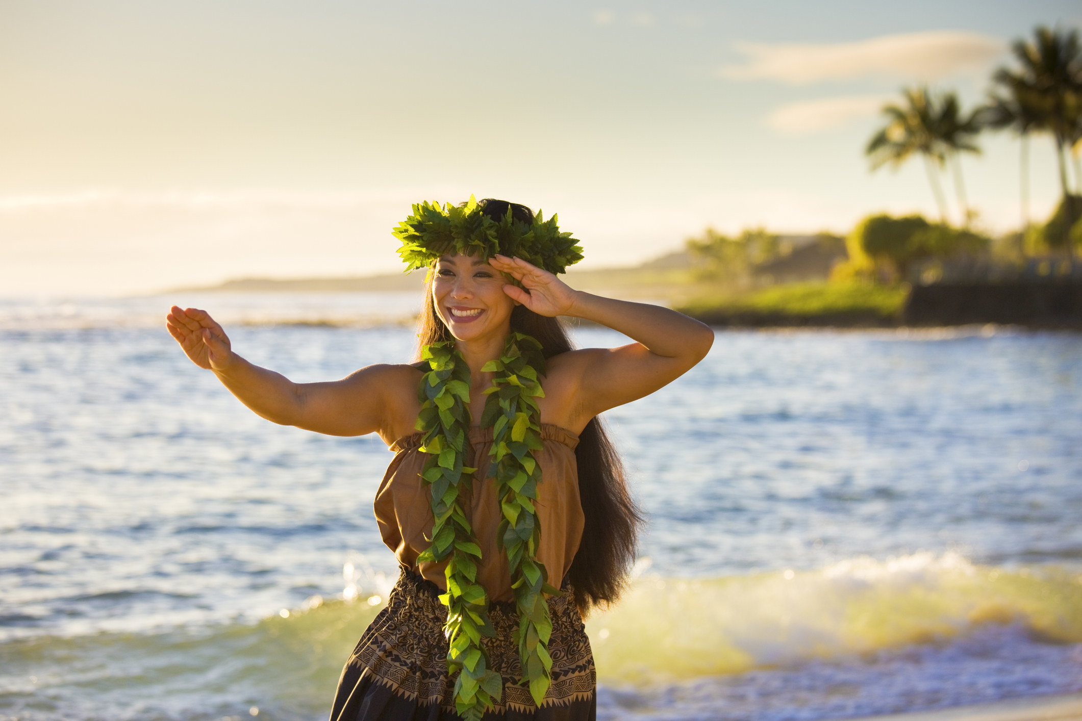 A woman smiles as she practices hula on a beach