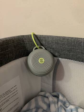 Reviewer photo of the white noise machine attached to a bassinet