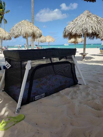 the travel crib set up on a beach