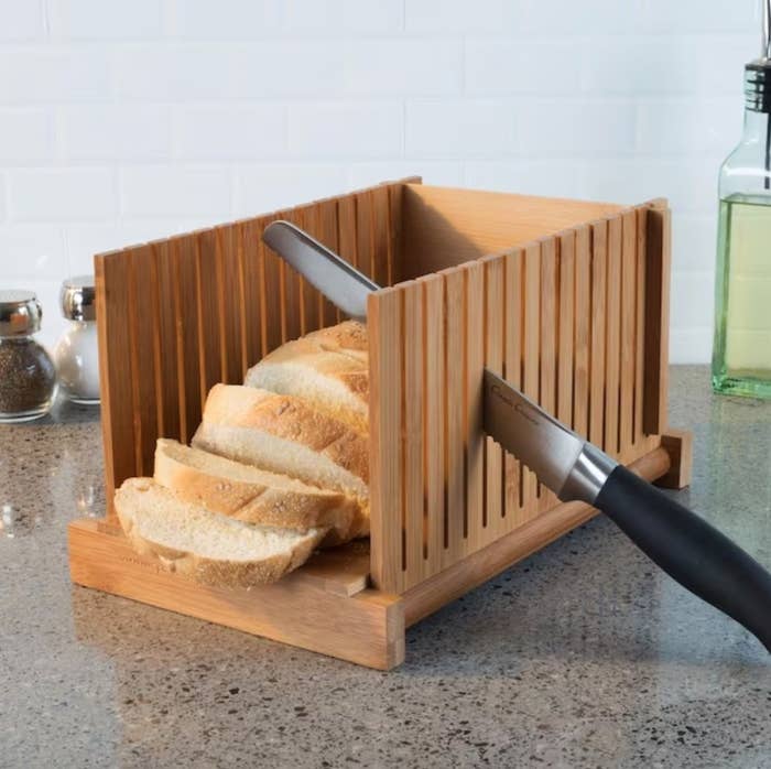 a wooden, slotted cutting block with bread and a knife inside