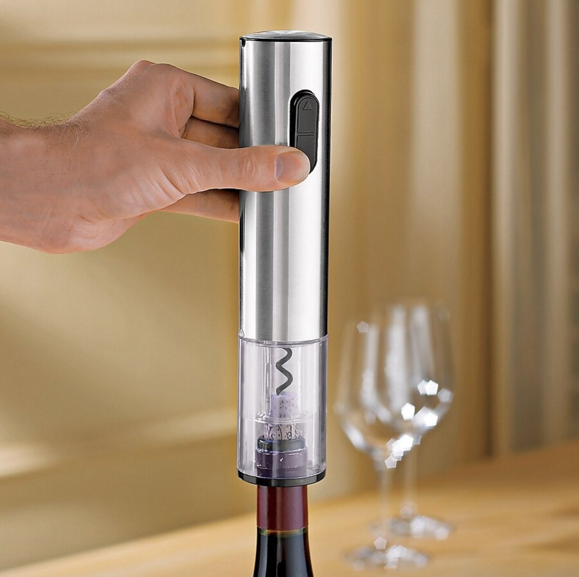 a person using an electric bottle opener to open a wine bottle
