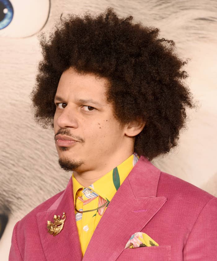 A closeup of Andre at an event wearing a brightly colored suit with a brooch and a printed shirt