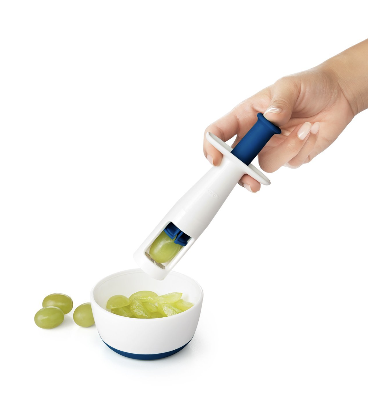 person cutting a grape with the tool into a bowl