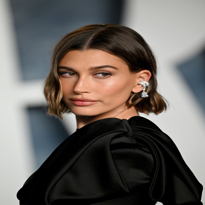 A closeup of Hailey looking over her shoulder as she poses for photographers on the red carpet. Hailey has a short blunt bob with a part down the middle