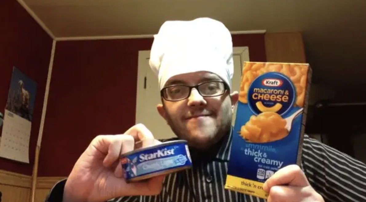 a person posing with a box of macaroni and cheese and a can of tuna