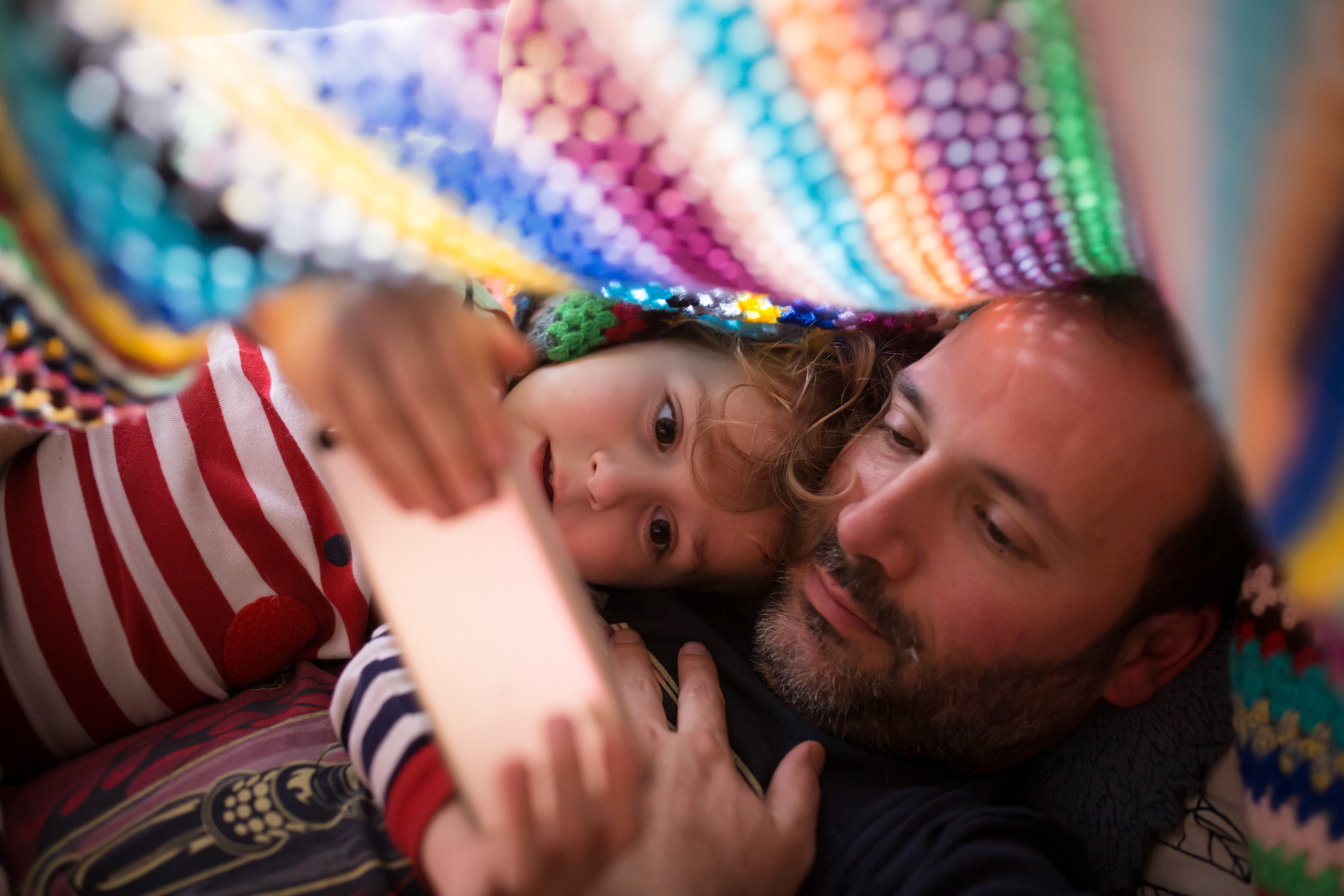 father and daughter playing a game under blanket fort