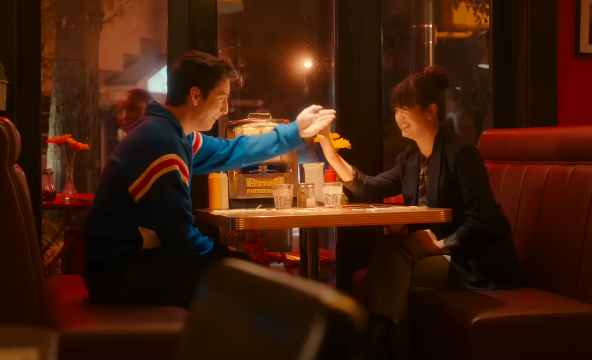 Two teenagers high five across a table at a diner