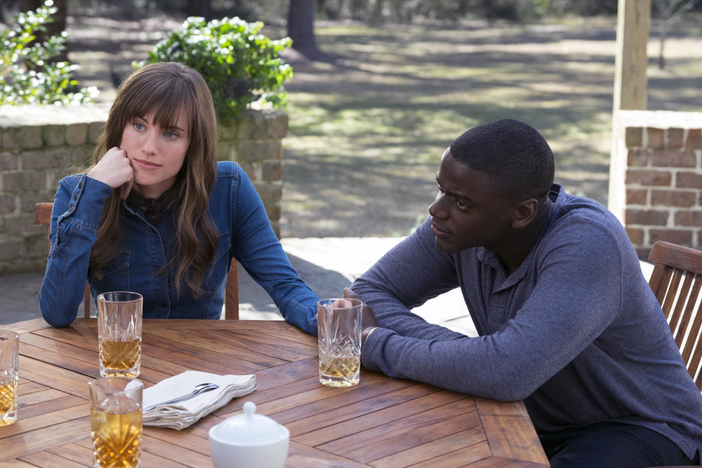 Allison Williams and Daniel Kaluuya sit at a patio table
