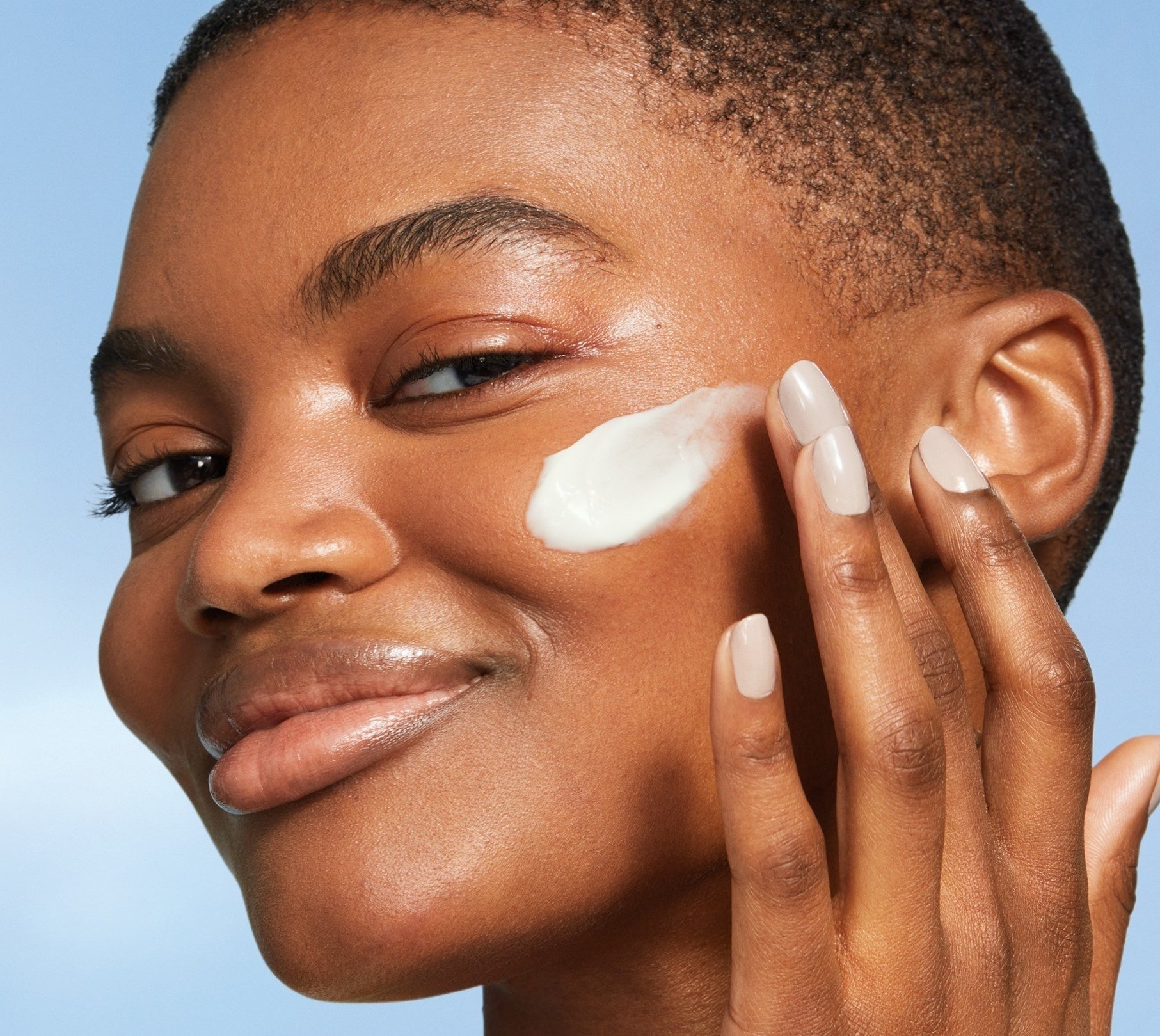Model applying white face cream to their face