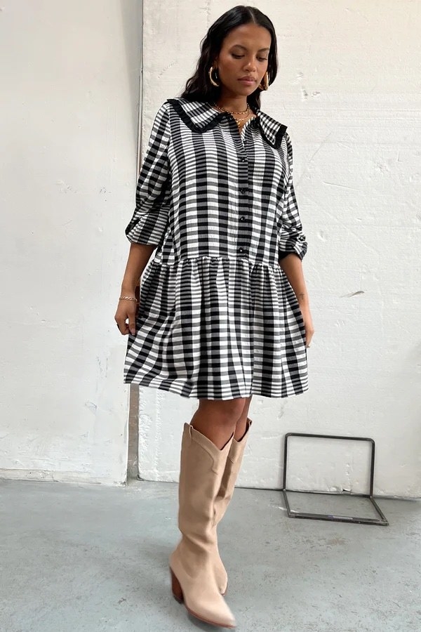 Model wearing black and white dress with tan boots