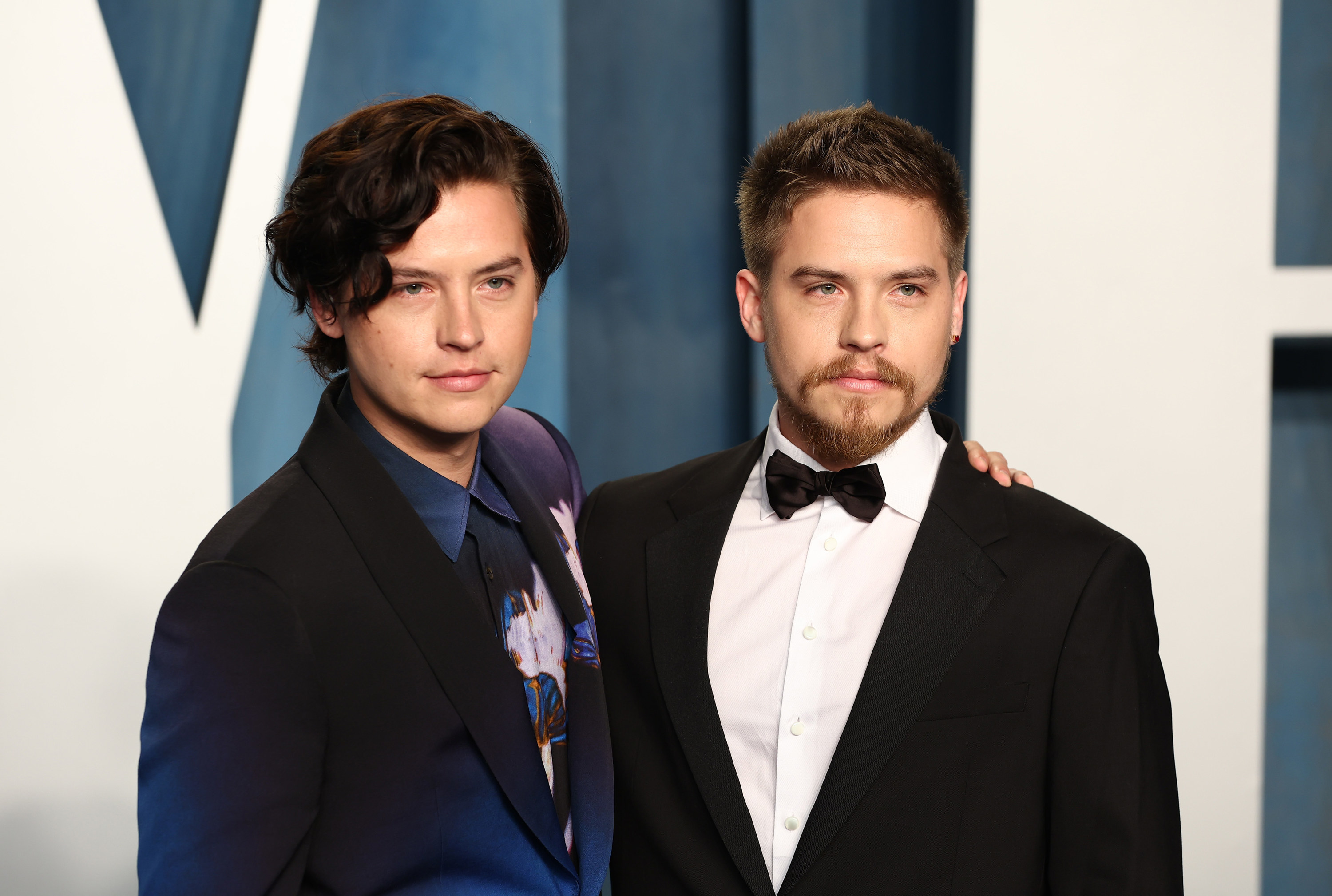 Head and shoulders shot of Cole and Dylan. Cole wears a black and navy gradient suit with a navy shirt while Dylan wears a classic black one with a bow tie and white shirt.