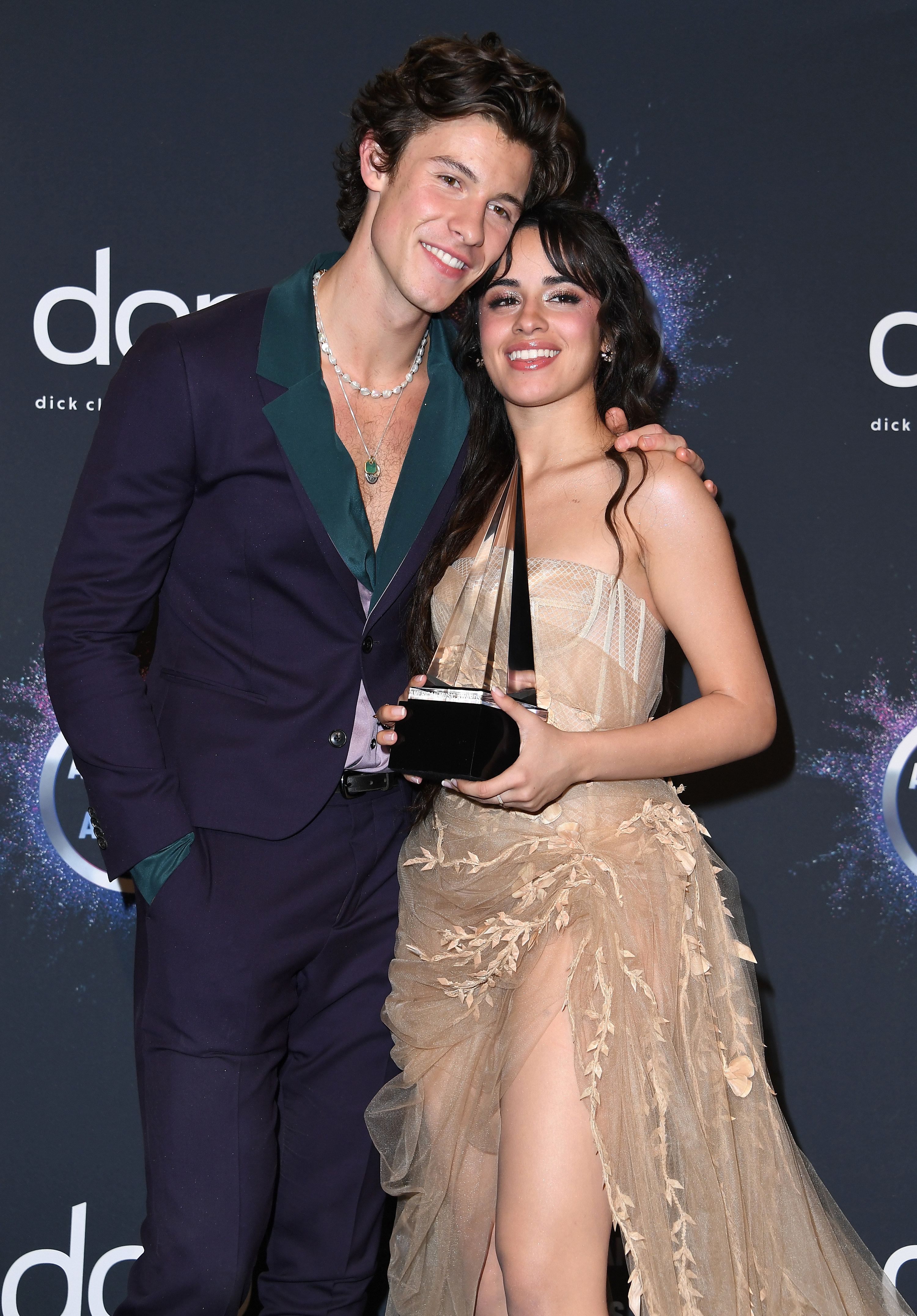 The former couple smiling as Camilla holds an American Music Awards on the red carpet