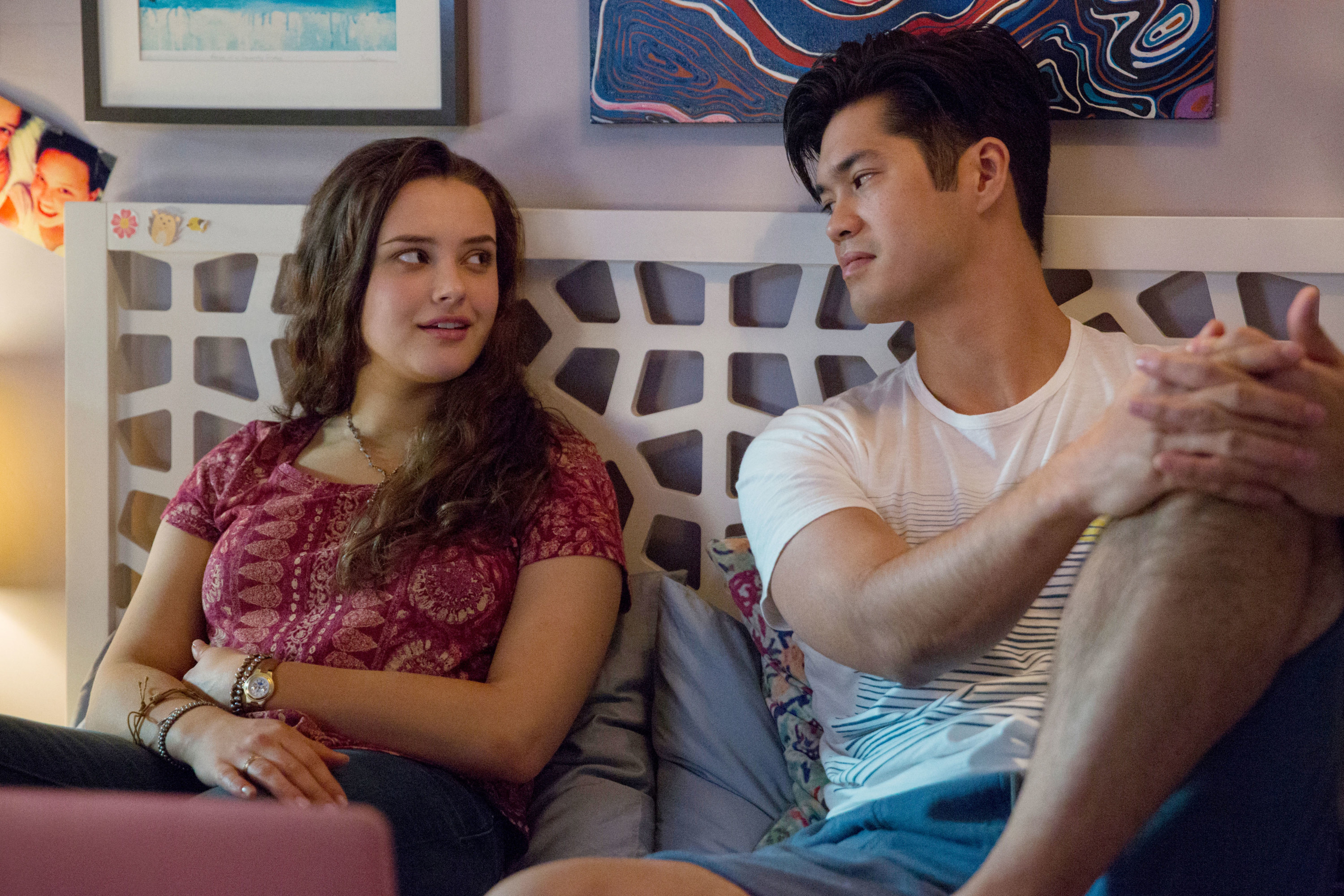 Katherine Langford chats with a boy while sitting on a bed