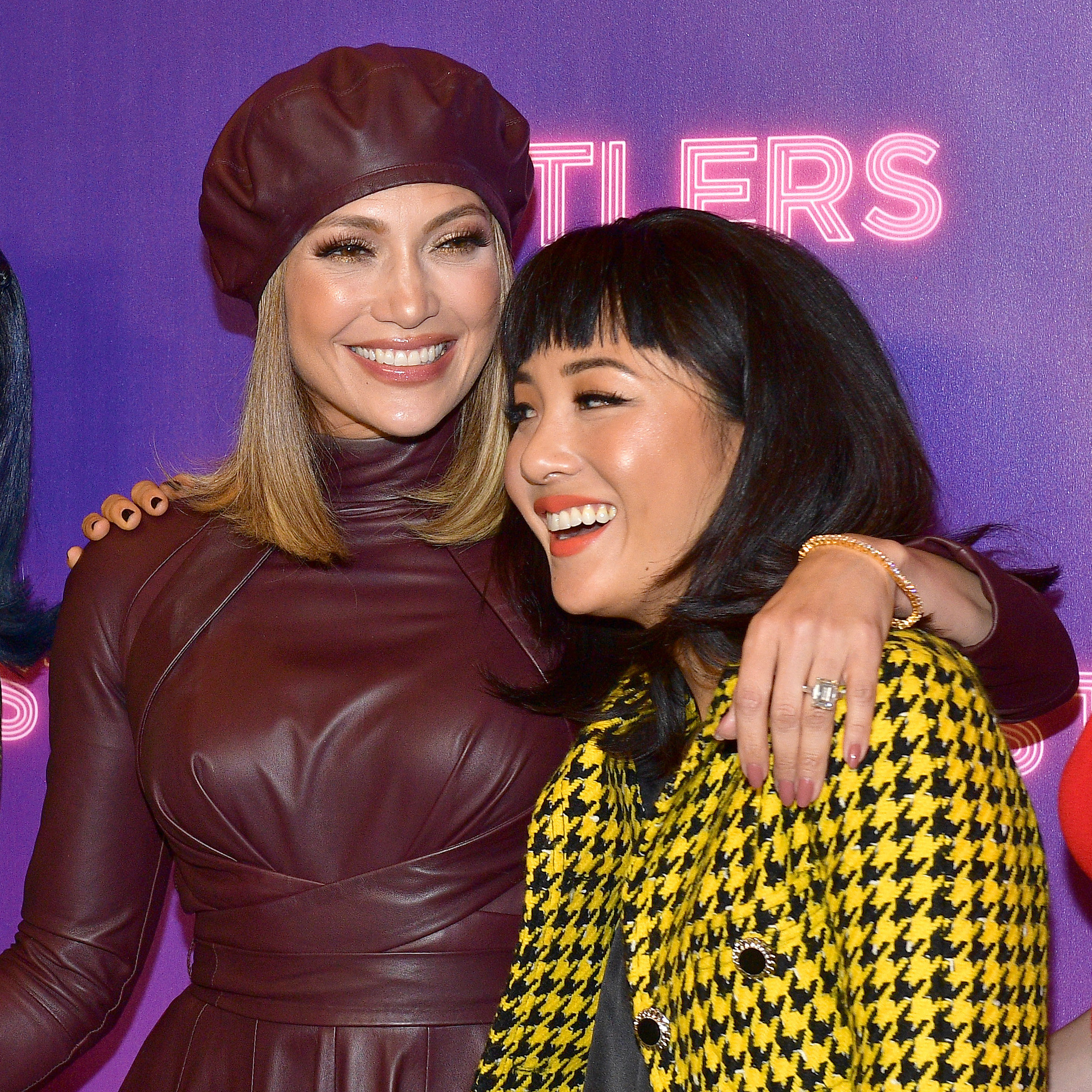 JLo and Constance Wu smile with their arms around each other at the premiere of Hustlers