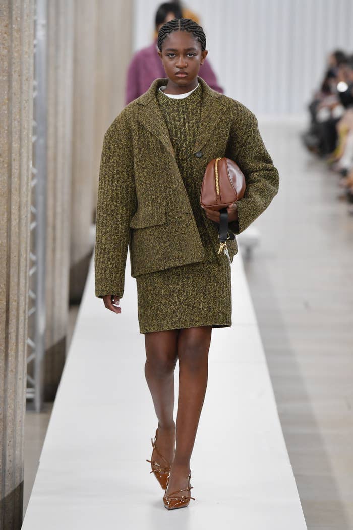 Zaya walking down the runway in a tweed dress and matching coat