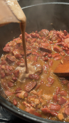 Thick bean puree being poured into the pot of beans