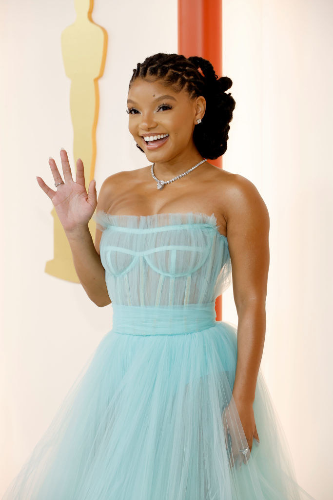 Halle smiling and waving in a sleeveless tulle dress