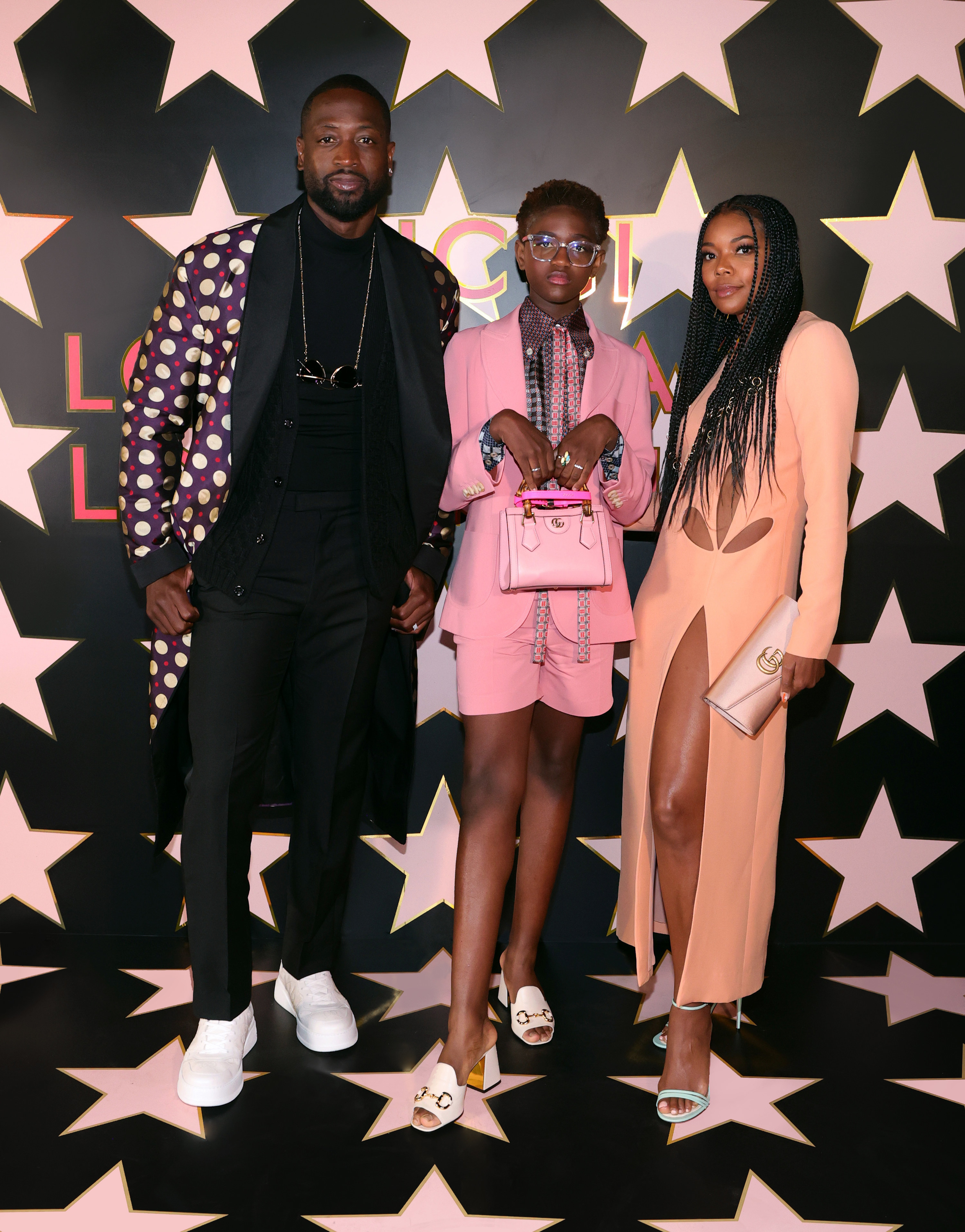 Zaya poses for a picture while standing between her parentes Dwyane and Gabrielle