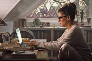 Sandra Bullock typing on a laptop as Loretta in The Lost City