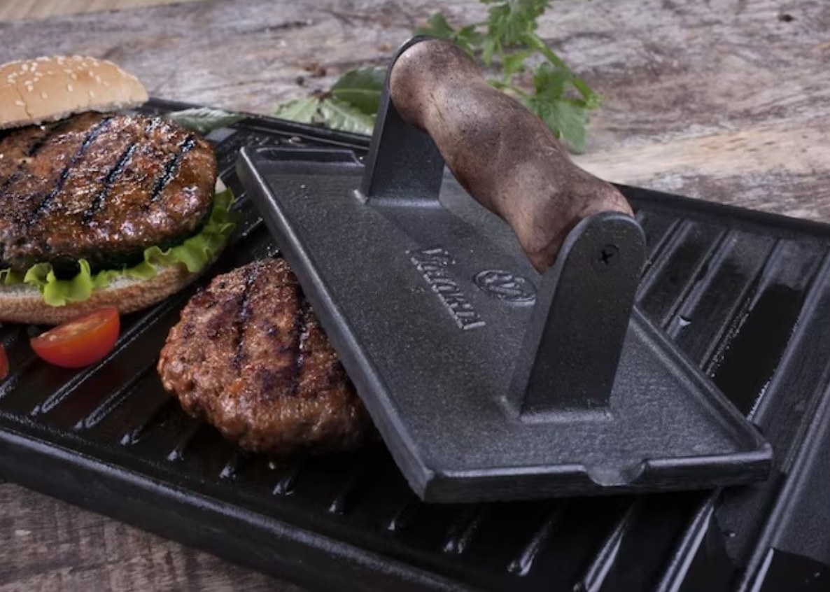 hamburger patties and a meat press on a griddle