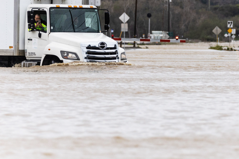 A truck driver drives through a flooded road, the water reaches its headlights