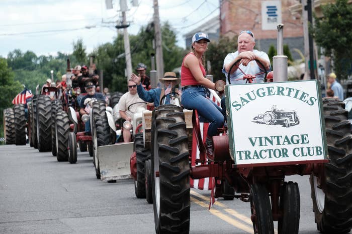 Tractors in the middle of the street with a sign that says &quot;Saugerties Vintage Tractor Club&quot;