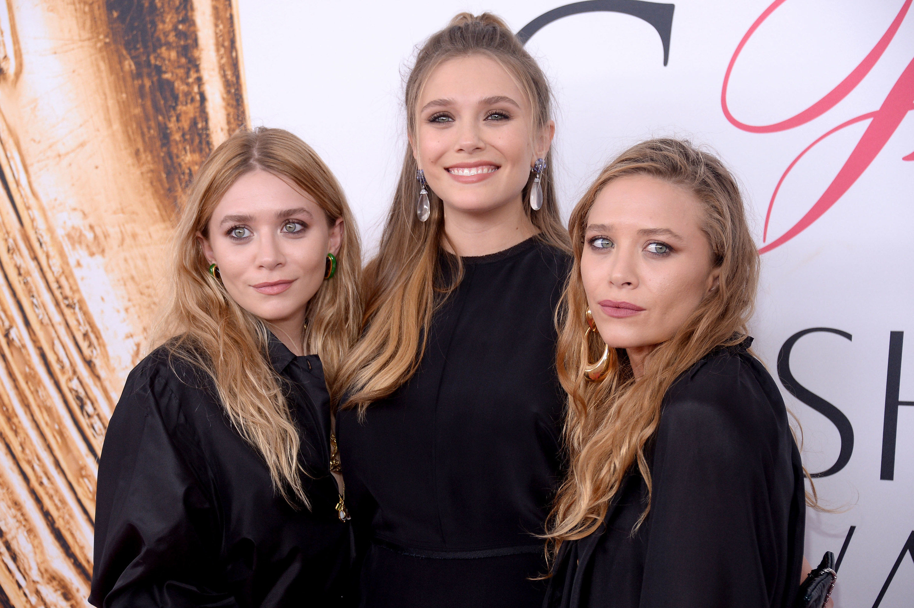 Ashley, Elizabeth and Mary Kate Olsen at an event. They are all wearing black high neck outfits