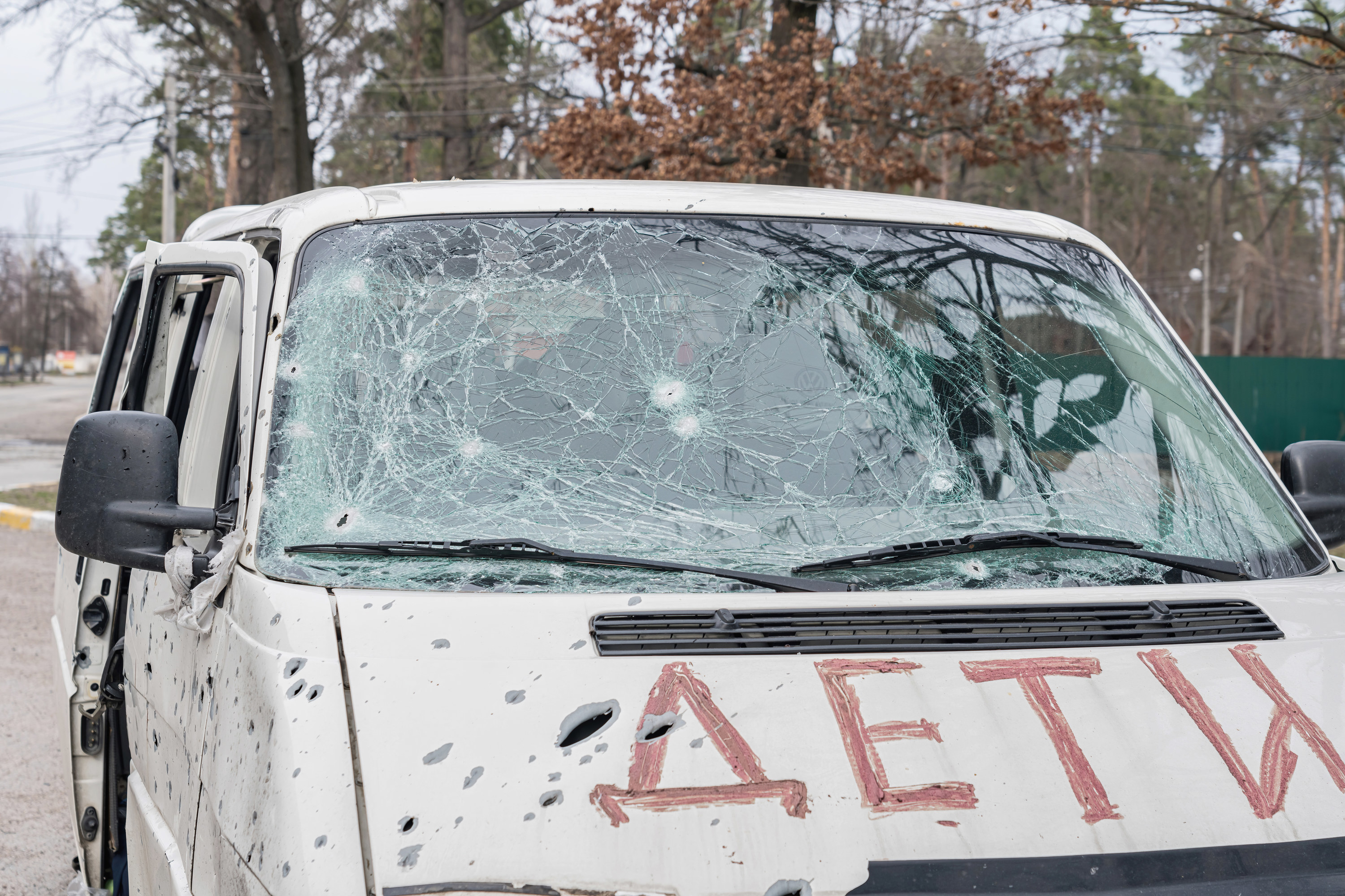 A white van with a smashed windshield has the word &quot;children&quot; in Ukrainian spelled on the hood