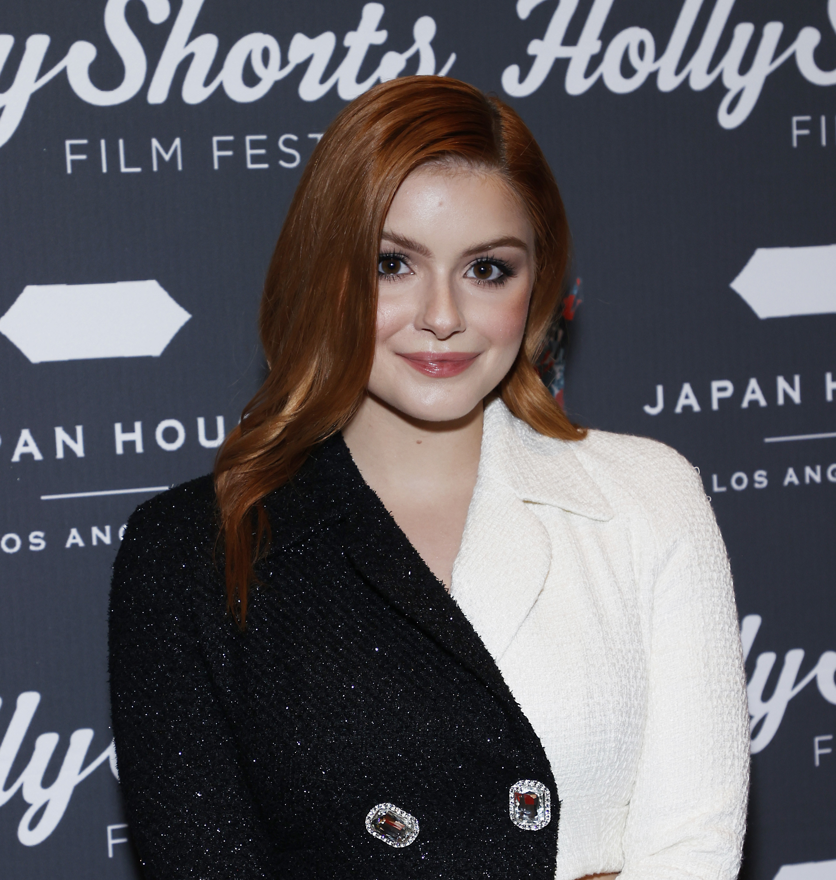 Ariel smiling at the camera, wearing a blazer jacket that&#x27;s black on one side and white on the other