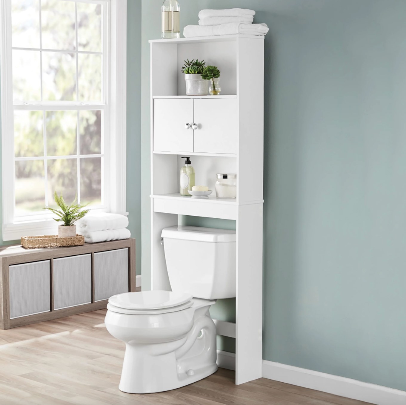 the white cabinet over a toilet in a decorated bathroom space