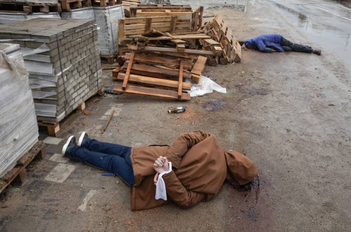 Two dead bodies in the street, one with hands bound behind their back