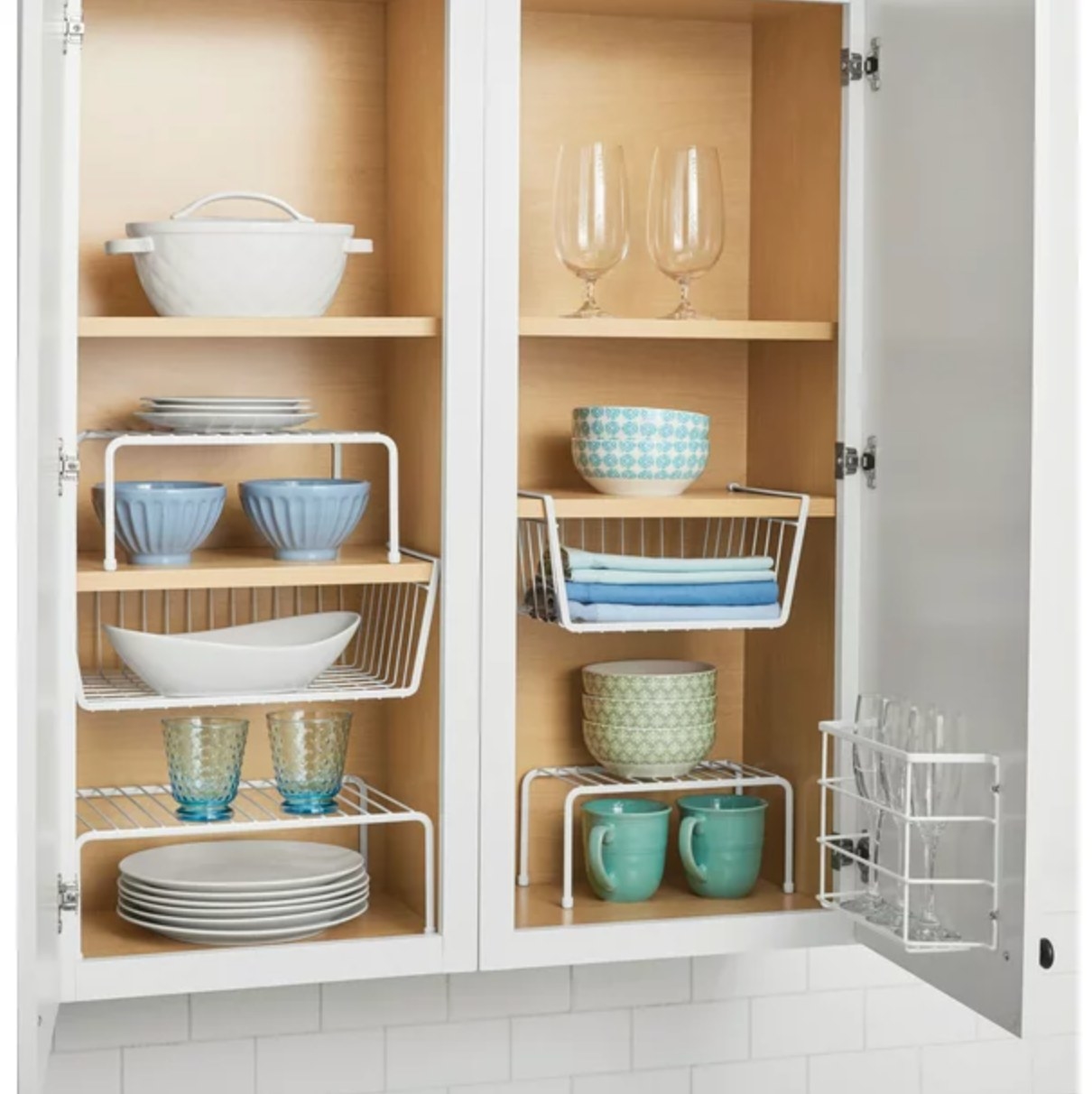the white wire shelves and hanging bins in a decorated cabinet space with blue and white dishware