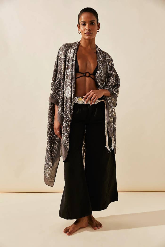 Model wearing brown patterned kimono with black bikini top and black pants