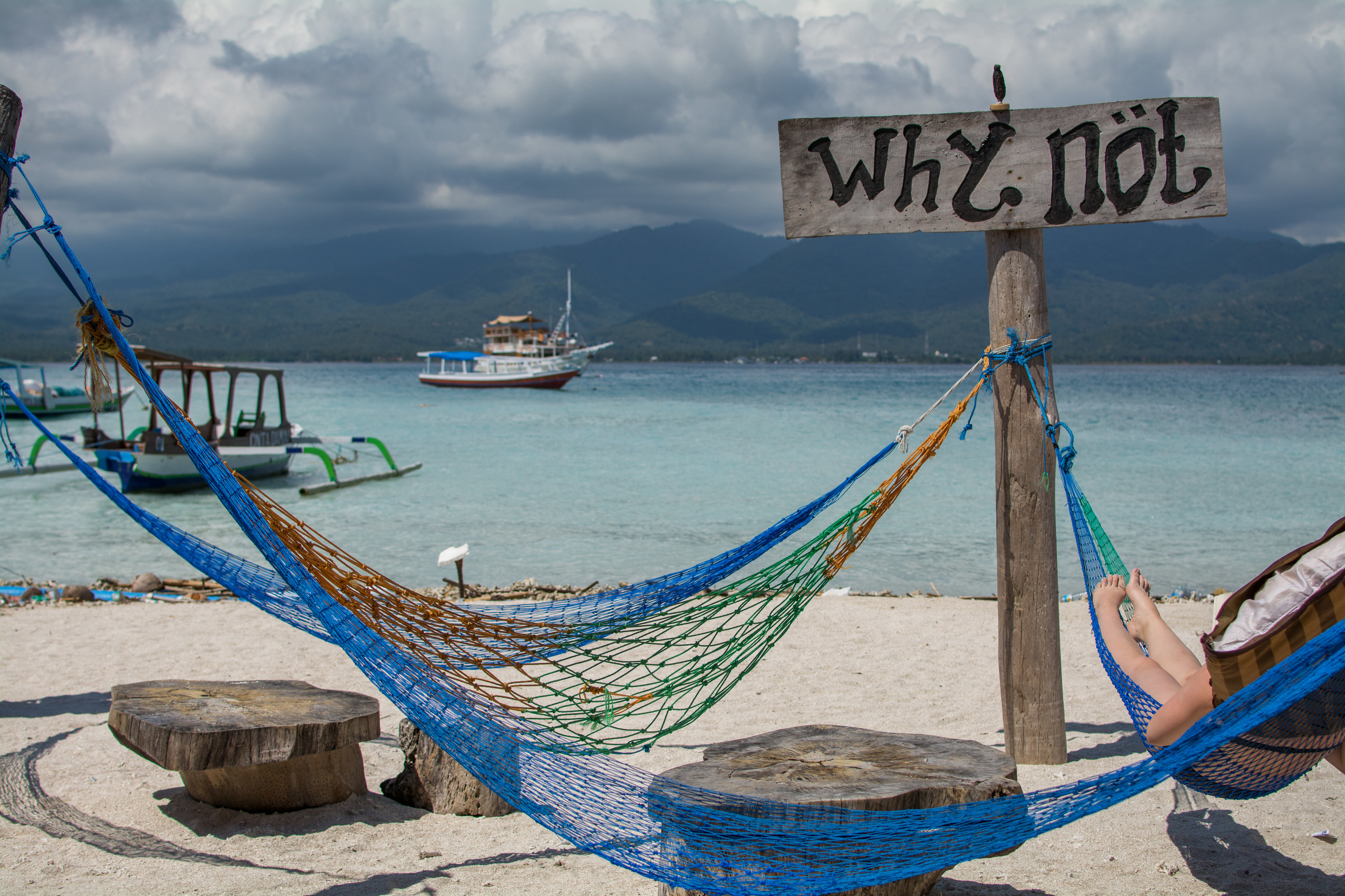 Hammocks in front of ocean with sign that says &quot;Why Not&quot;