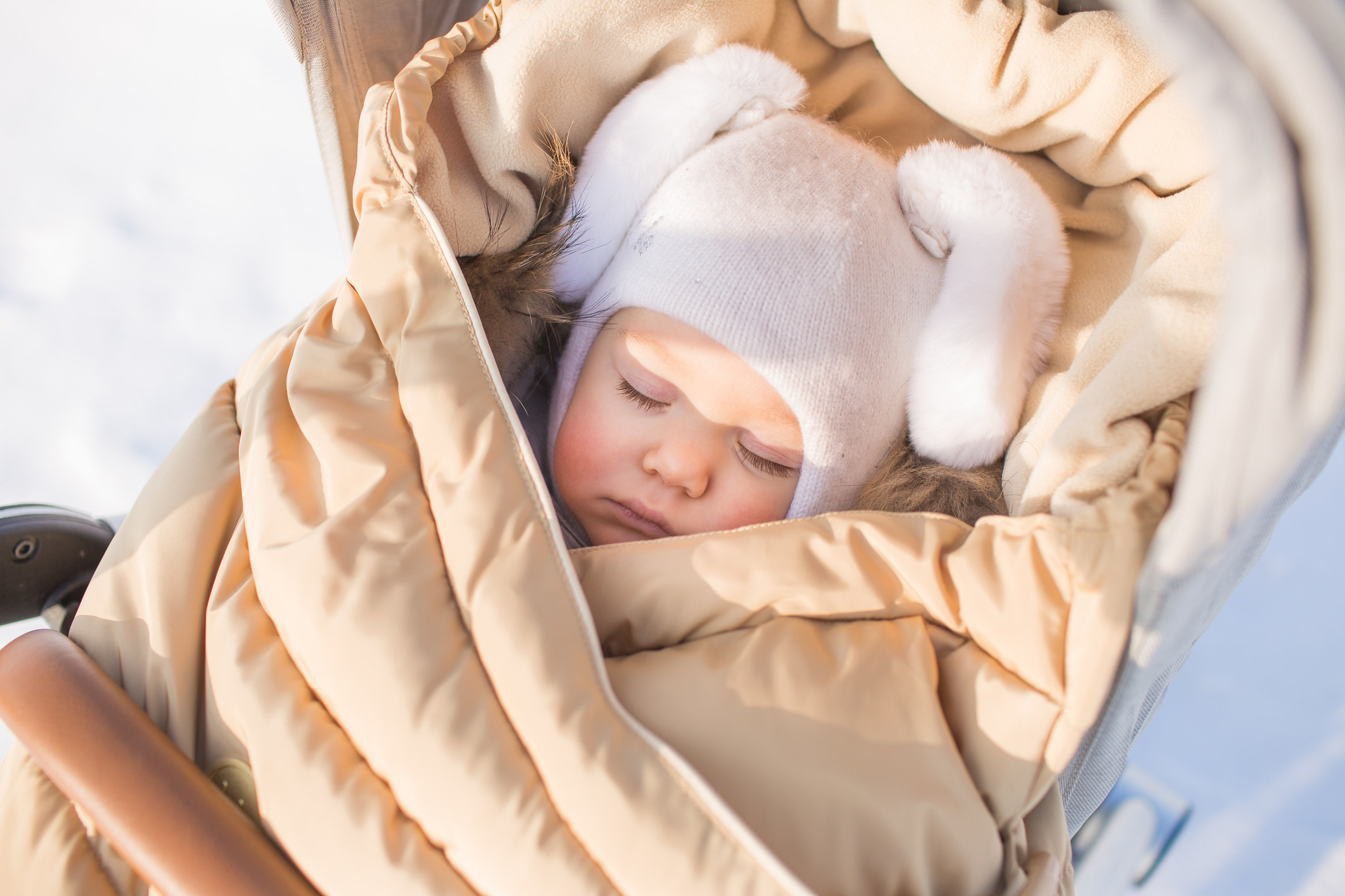 A baby bundled up for winter asleep in a stroller.