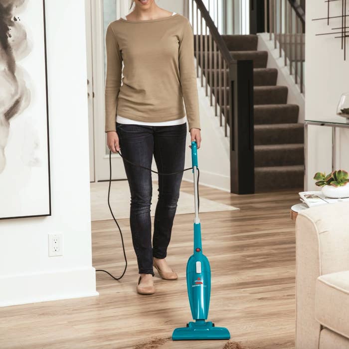 a model using the small teal vacuum in a decorated living room