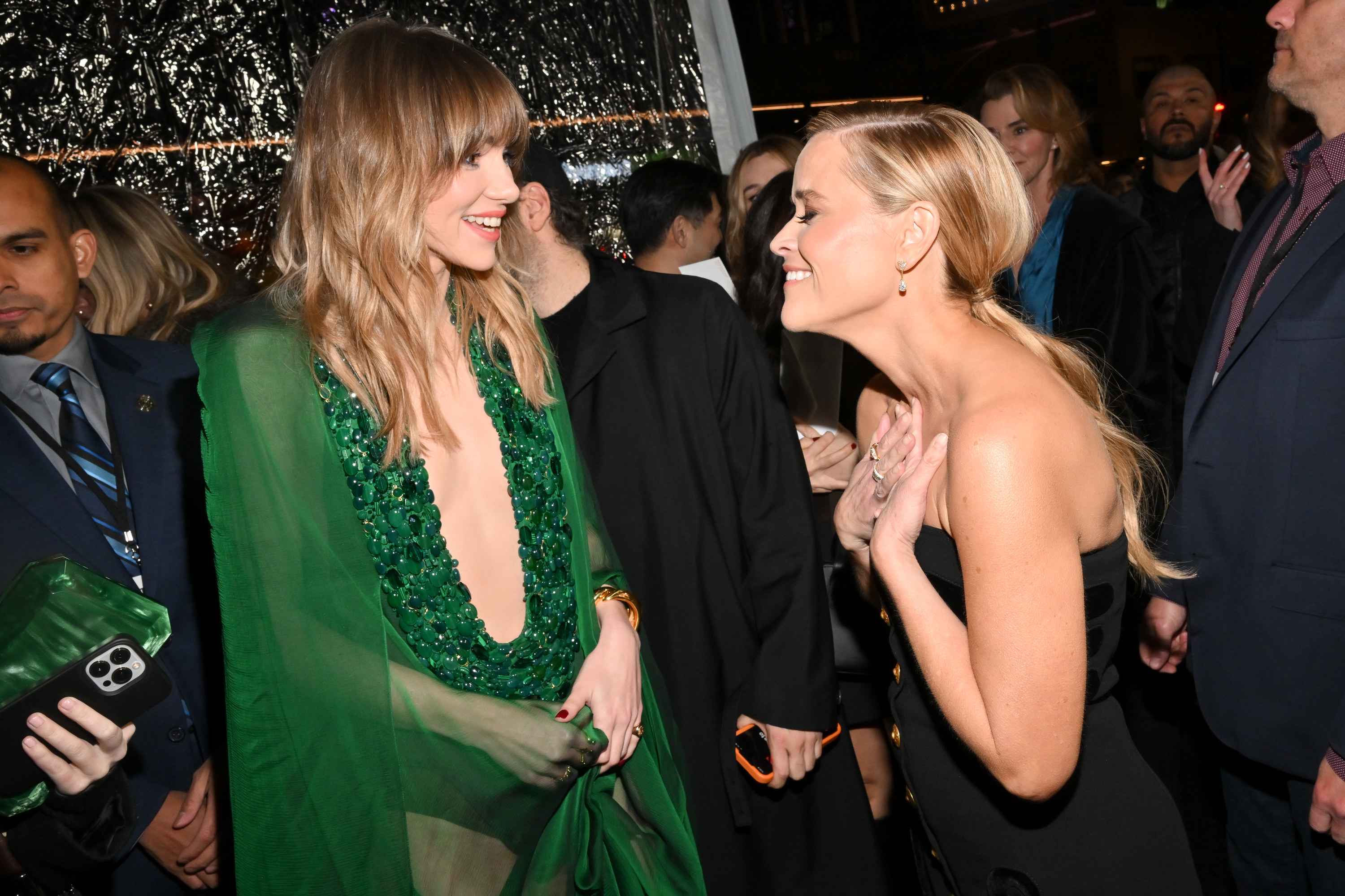 Reese holding her hands to her heart and smiling at Suki Waterhouse
