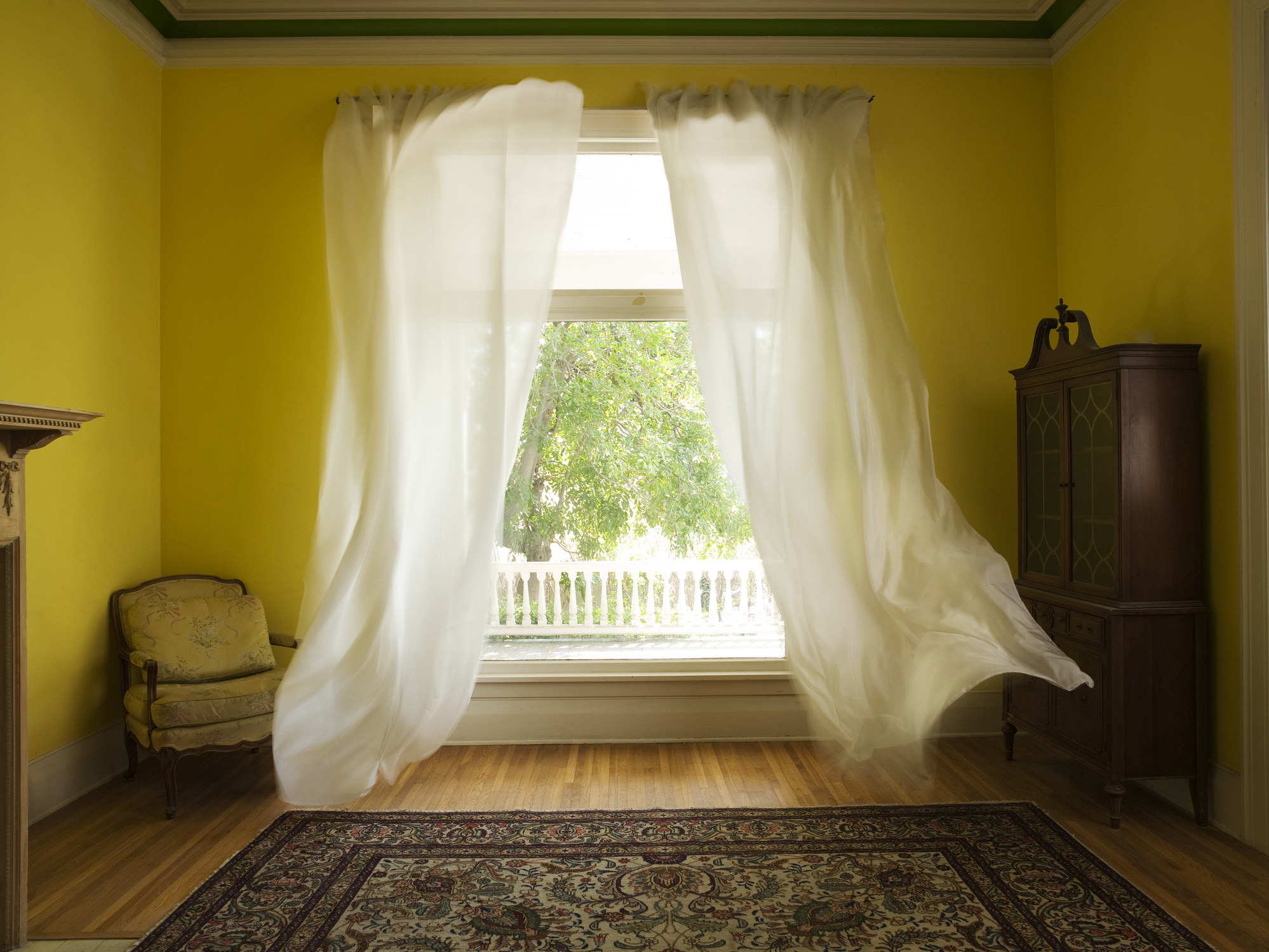Room with curtains billowing at open window.
